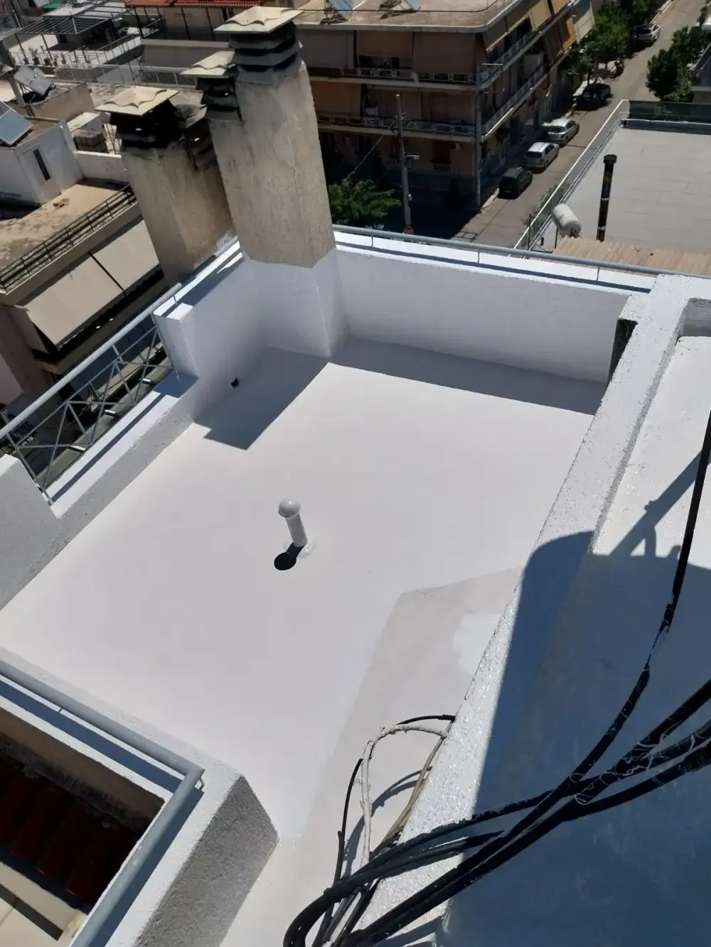 Impermeabilização de laje com manta líquida branca, subindo pelas muretas da cobertura